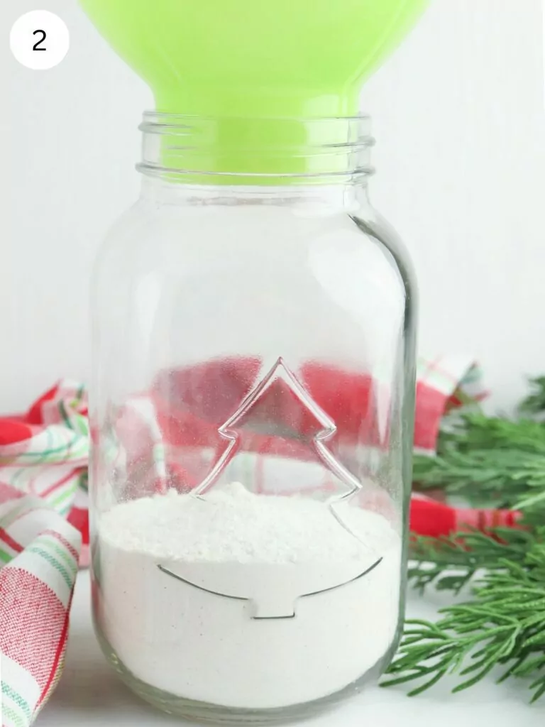 green funnel in mason jar with flour.