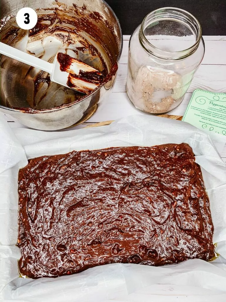 Unbaked brownies in pan with parchment paper.